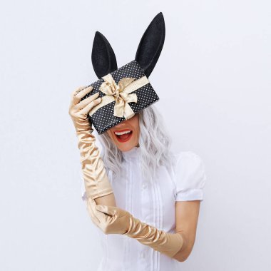 Beyaz uzayda Sihirli Gülümseyen Tavşan Kadın kışın hediye kutusunu tutuyor. - Sürpriz. Minimum moda festivali Noel / Yeni Yıl, tatiller, doğum günü partisi, kutlama konsepti.