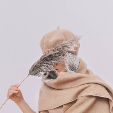 Günlük görünüşün şehvetli ve şık ayrıntıları. Günlük bej kıyafetler giyen bir manken. Bere ve eşarp. Moda minimalist tarzı. Tam bir bej estetiği. Moda kitabı. Sıcak Sonbahar Kış Mevsimleri
