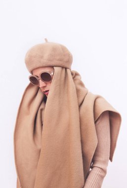 Şık bir Paris hanımı. Günlük bakışın ayrıntıları. Günlük bej elbiseli bir model. Bere ve eşarp. Modaya uygun güneş gözlükleri. Minimalist stil. Tam bir bej estetiği. Moda kitabı. Sıcak Sonbahar Kış Mevsimleri konsepti