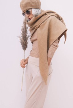 Günlük görünüşün şık ayrıntıları. Günlük bej kıyafetler giyen bir manken. Bere, eşarp ve gözlük. Moda minimalist tarzı. Bej estetiği. Moda kitabı. Sıcak Sonbahar Kış Mevsimleri