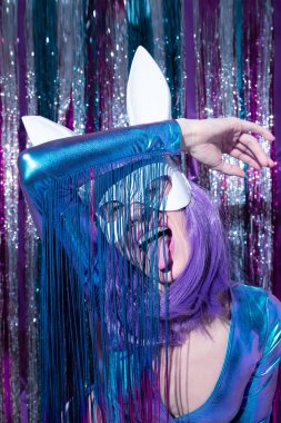 Playful Disco Girl 80 'lerin modaya uygun holografik parti görüntüsü ve tavşan maskesi. Tinsel kurulum. Yeni yılın kulüp konsepti. Mutlu noeller. Tatil günü. Moda ve ışıltı, yıldızların eski moda modunda.