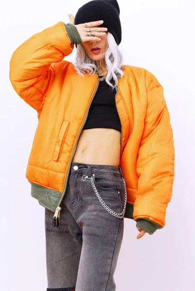 Blonde girl in fashion urban street look. Trendy orange bomber and stylish Ripped jeans. Fall winter seasons lookbook