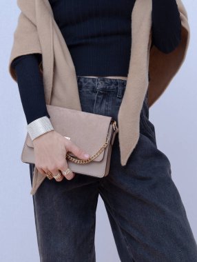 Gündelik sonbahar kış kıyafetleri giymiş bir manken. Moda minimalist tarzı. Günlük bakışın ayrıntıları. Moda bej rengi yün atkı ve el çantası.