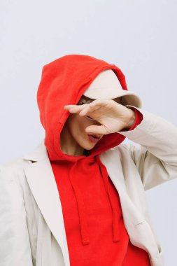 Stüdyoda manken. Kırmızı kapüşonlu, modaya uygun bir kış kıyafeti. Kaptan. Sokak stili. Moda arama kitabı konsepti
