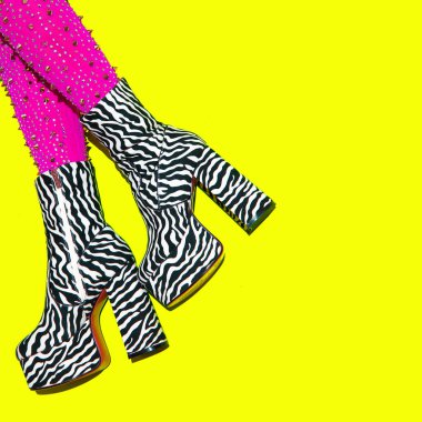 Topuklu ayakkabı giymiş moda bacaklar, sarı arka planda zebra desenli botlar. Şık bir gece kulübü havası. Go-go Kızlar. Kabare. Parti sonrası konsept