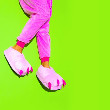Pembe kigurumi pijama ve terlik giymiş bacaklar. Evde kal. Pijama partisi konsepti. Minimum moda şeker komik sanat
