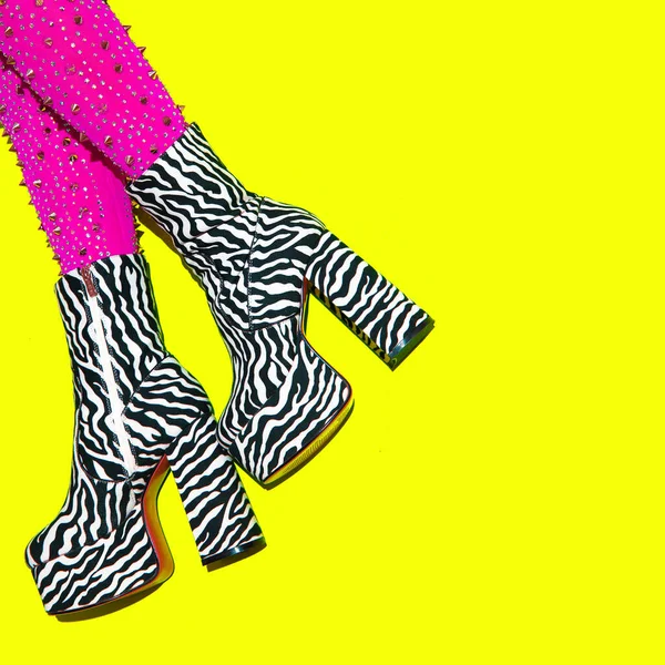 Fashion legs in heel party zebra print boots on yellow minimal background. Stylish clubbing mood.  Go-go Girls. Cabaret. After party concept