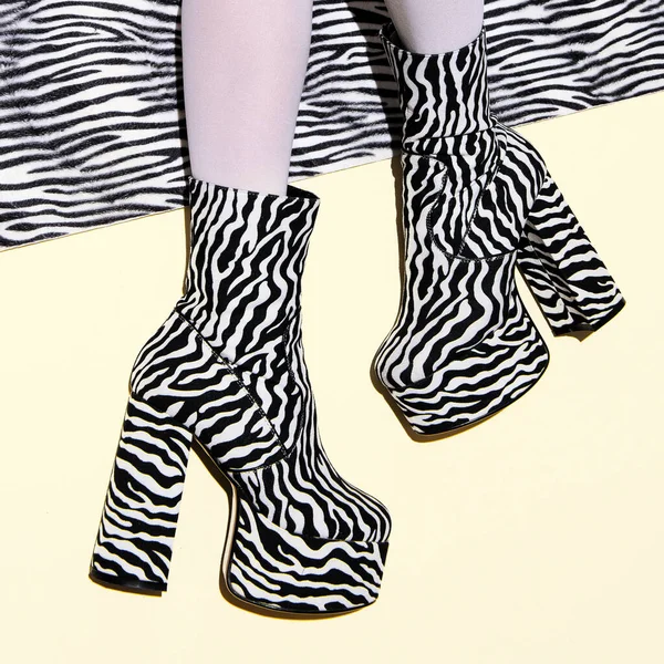 Fashion legs in heel party zebra boots on  minimal background. Animal texture print. Stylish tropical concept