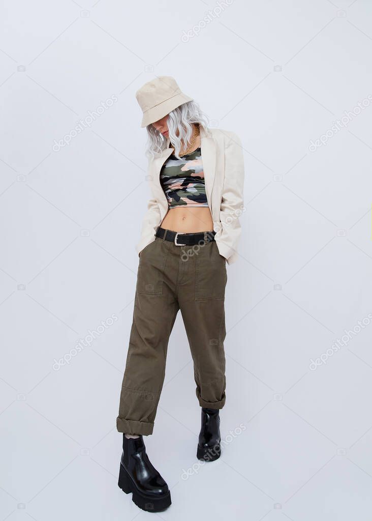 Portrait of young blond woman wearing military fashionable street style clothing and trendy platform boots. Minimalist fashion