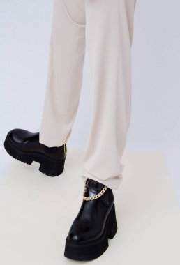 Sonbahar kıyafetlerinin modaya uygun ayrıntıları. Bej pantolon giyen ve şık siyah çizme giyen bir kadın. Her gün bak. Sokak modası konsepti. Yüzü yok.