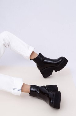 Sonbahar kıyafetlerinin modaya uygun ayrıntıları. Beyaz kot giyen ve şık siyah çizmeli bir kadın. Her gün bak. Sokak modası konsepti. Yüzü yok. Minimalist.