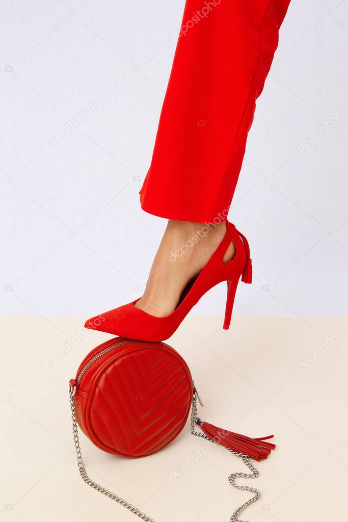 Fashion unrecognizable Lady in retro red pants and shoes. Studio lookbook. Trendy Accessories clutch. Minimalist elegant vintage details style.