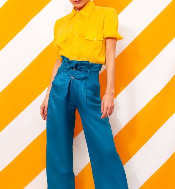 Renkli sarı arka planda modaya uygun giyinmiş bir model. Minimal moda bahar yaz konsepti. Renk kombinasyonu.