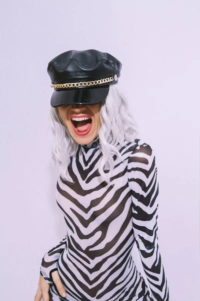 フリークスタイリッシュなゼブラプリントの服や白いスタジオでポーズ革のトレンディーな黒のキャップで遊び心のある幸せなアンドロゲンモデル クラブパーティースタイル — ストック写真