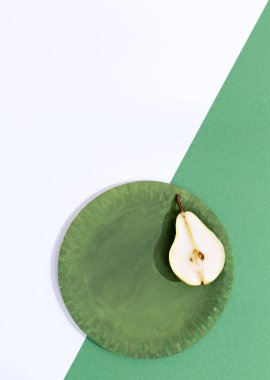 Taze minimalist sahne. Yeşil tabakta organik armutlar ve iki renkli kağıt arka plan. Sıfır atık, biyoloji, çevre, vegan konsept. Kaliteli düz duvar kağıdı