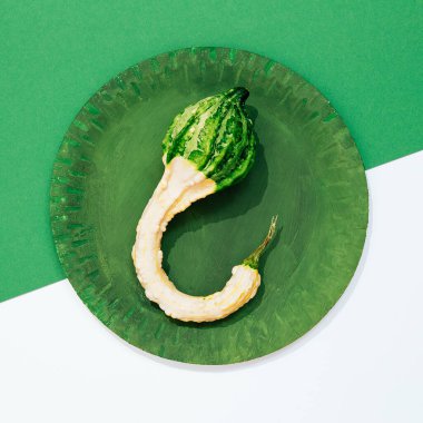 Taze minimalist sahne. Yeşil tabakta organik balkabağı ve kağıt geometri arka planı. Sıfır atık, biyoloji, çevre, vegan konsept. Gösterişli düz pankart