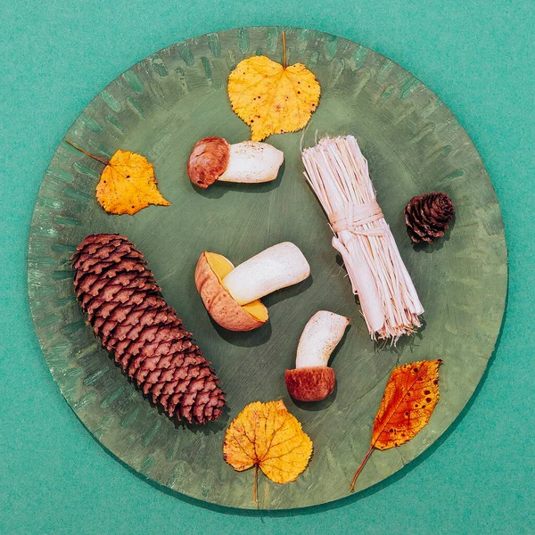 Sonbahar minimalist sahnesi. Sonbahar dekoru mantarları ve yeşil tabakta yaprak ve kağıt arka plan. Mevsimsel konsept. Kaliteli düz yatak