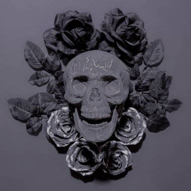 Tek renkli arka planda siyah çiçekler ve kafatası dekoru kompozisyonu. Şık düz döşeme sahnesi