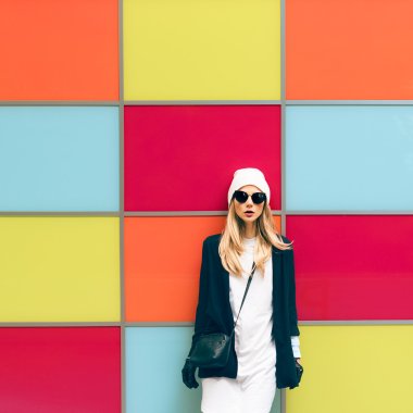 Fashionable blonde standing against a bright wall. urban style clipart