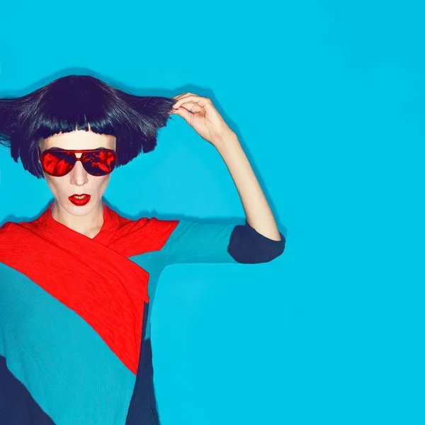 Brunette model with fashion haircut and sunglasses on a blue bac — Stock Photo, Image