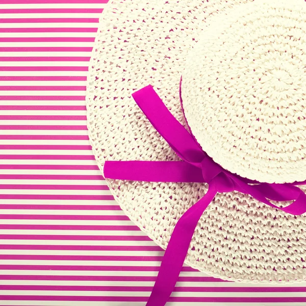 White straw sunhat on a striped magenta background Royalty Free Stock Photos