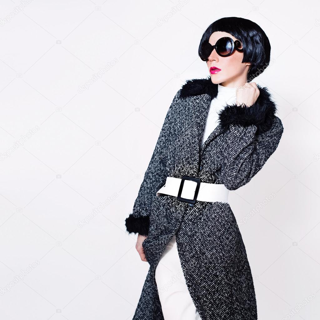 Lady in stylish sunglasses and fashionable coat on a white backg