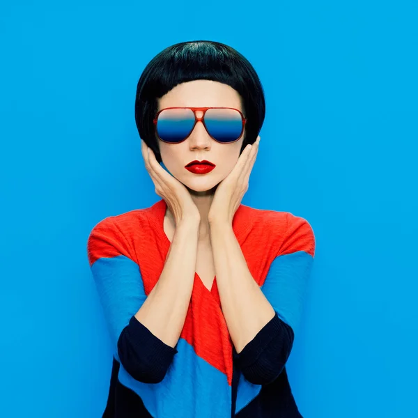 Brunette lady with fashion haircut and sunglasses on a blue back — Stock Photo, Image