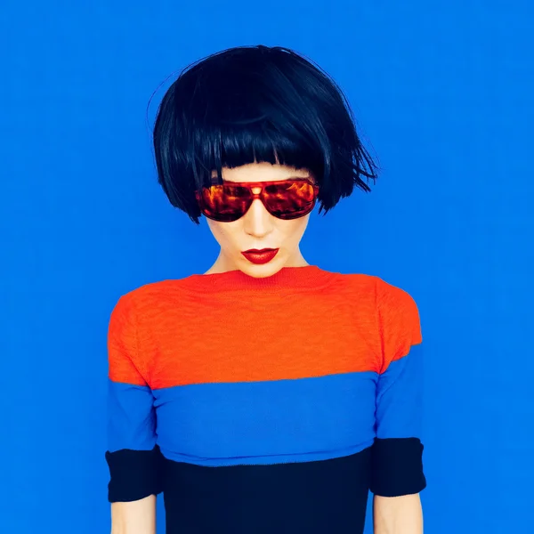 Brunette with fashionable hairstyle and sunglasses on a blue bac — Stock Photo, Image