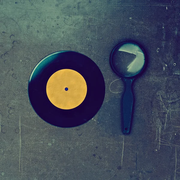 Vinyl record and magnifier on wooden table — Stock Photo, Image