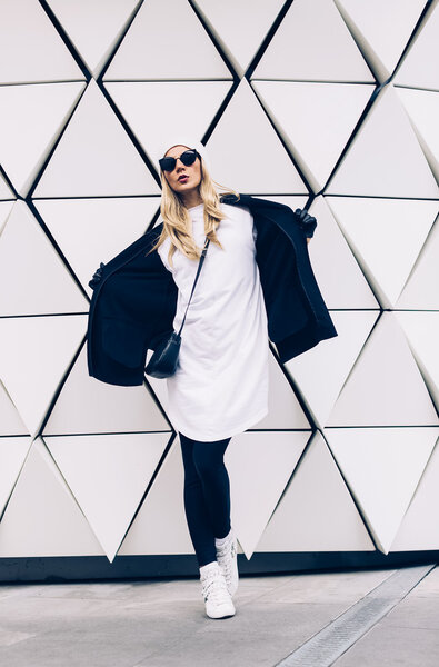 Glamorous blonde standing at the wall. Urban fashion black and white