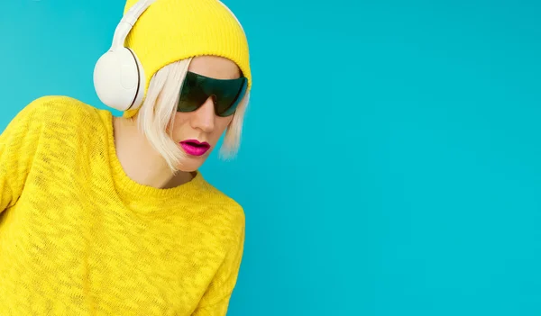 Glamurus blonde DJ en vêtements lumineux écoutant de la musique sur bleu — Photo