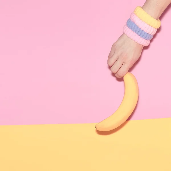 Mano sosteniendo un plátano. Moda, minimalismo estilo vainilla — Foto de Stock