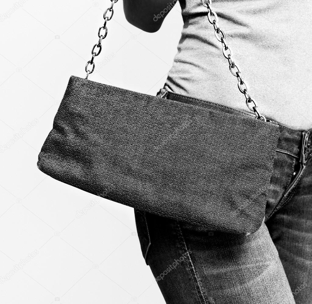 Girl in jeans with trendy clutch. black and white photo