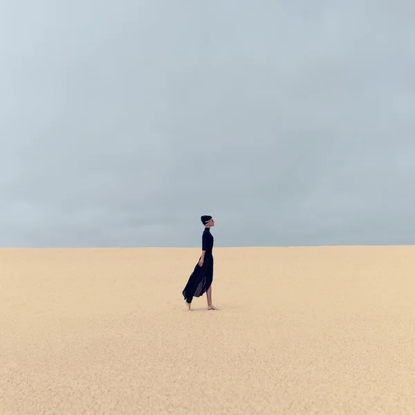 Stylish girl in black clothes walking in the desert — Stock Photo, Image