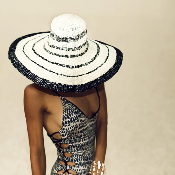 Λαμπερό μαυρισμένο κυρία σε ένα καπέλο μόδας μαγιό στην παραλία — Φωτογραφία Αρχείου