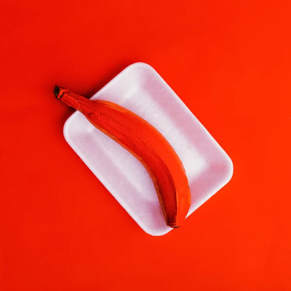 Fausse banane rouge sur fond rouge. style minimal — Photo