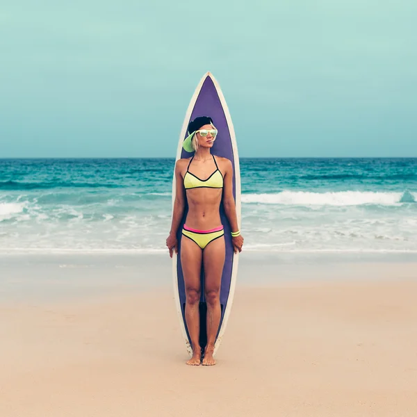 Дівчина в модному купальнику, що стоїть на пляжі з серфінгом — стокове фото