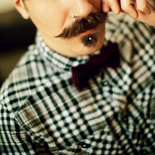 Stylish vintage man. Bow, checkered shirt and a mustache.