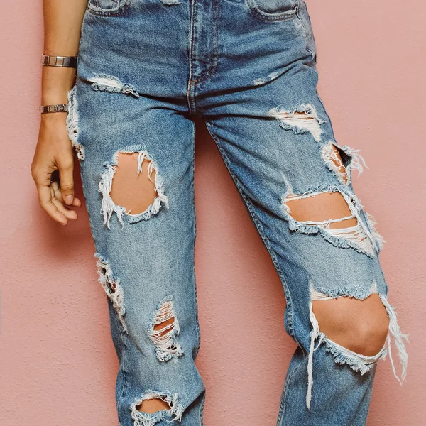 Senhora na moda rasgado jeans stands na parede rosa — Fotografia de Stock