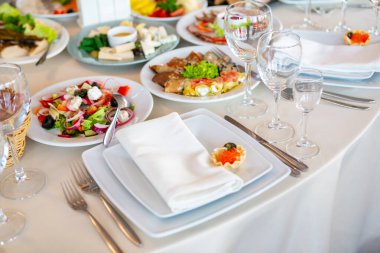 Konuklar için hazırlanmış, salata ve başlangıç yemeklerinin de dahil olduğu bir dizi yemek sergilenen güzel bir masa..