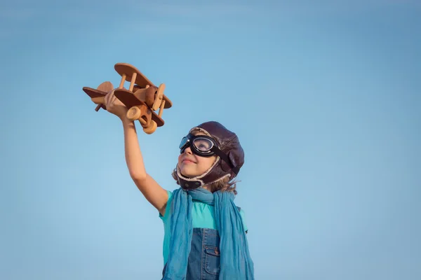 Счастливый ребенок играет с деревянным игрушечным самолетом — стоковое фото