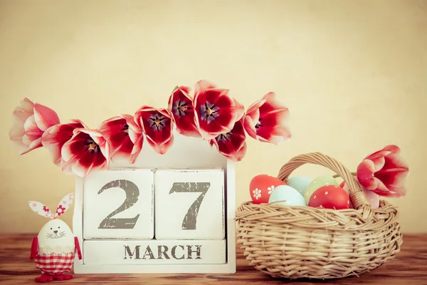 Cesto di uova di Pasqua e fiori sul tavolo di legno — Foto Stock