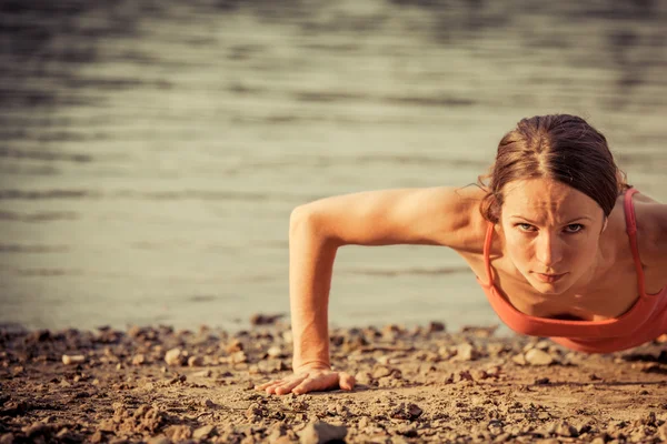 Silná žena dělá push up na pláži — Stock fotografie