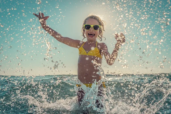 Criança feliz brincando no mar — Fotografia de Stock