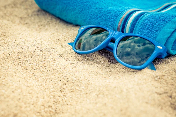 Ręcznik i okulary przeciwsłoneczne na plaży — Zdjęcie stockowe