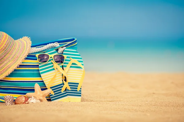 Chinelos e bolsa na praia arenosa — Fotografia de Stock