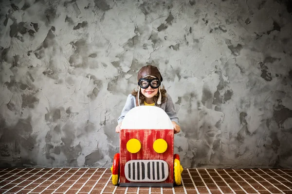 Criança dirigindo em um carro feito de caixa de papelão — Fotografia de Stock