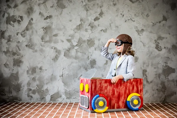 Niño conduciendo en un coche hecho de caja de cartón — Foto de Stock