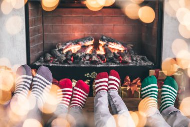Noel 'de şöminenin yanında çocukları olan mutlu bir aile. Yılbaşı çorabı giyen ayaklar. Kış tatili kavramı