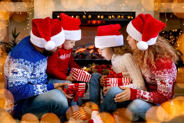 Happy family with children near fireplace at Christmas. Mother, father and kids having fun at home. Xmas holiday concept